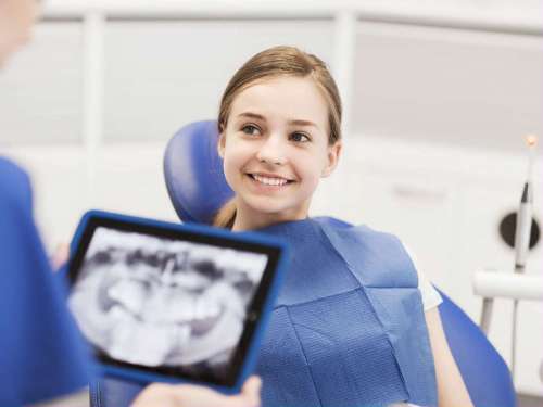 girl in dental chair discussing digital x-rays with dentist